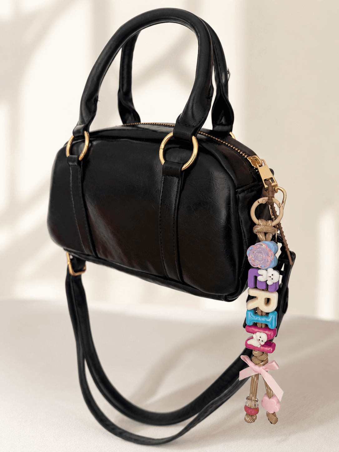 Custom keyring spelling ARIA on a black handbag